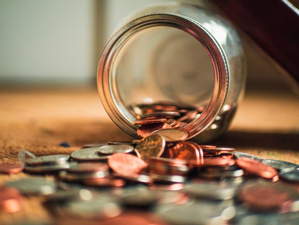 A jar of coins spilled onto a carpet.